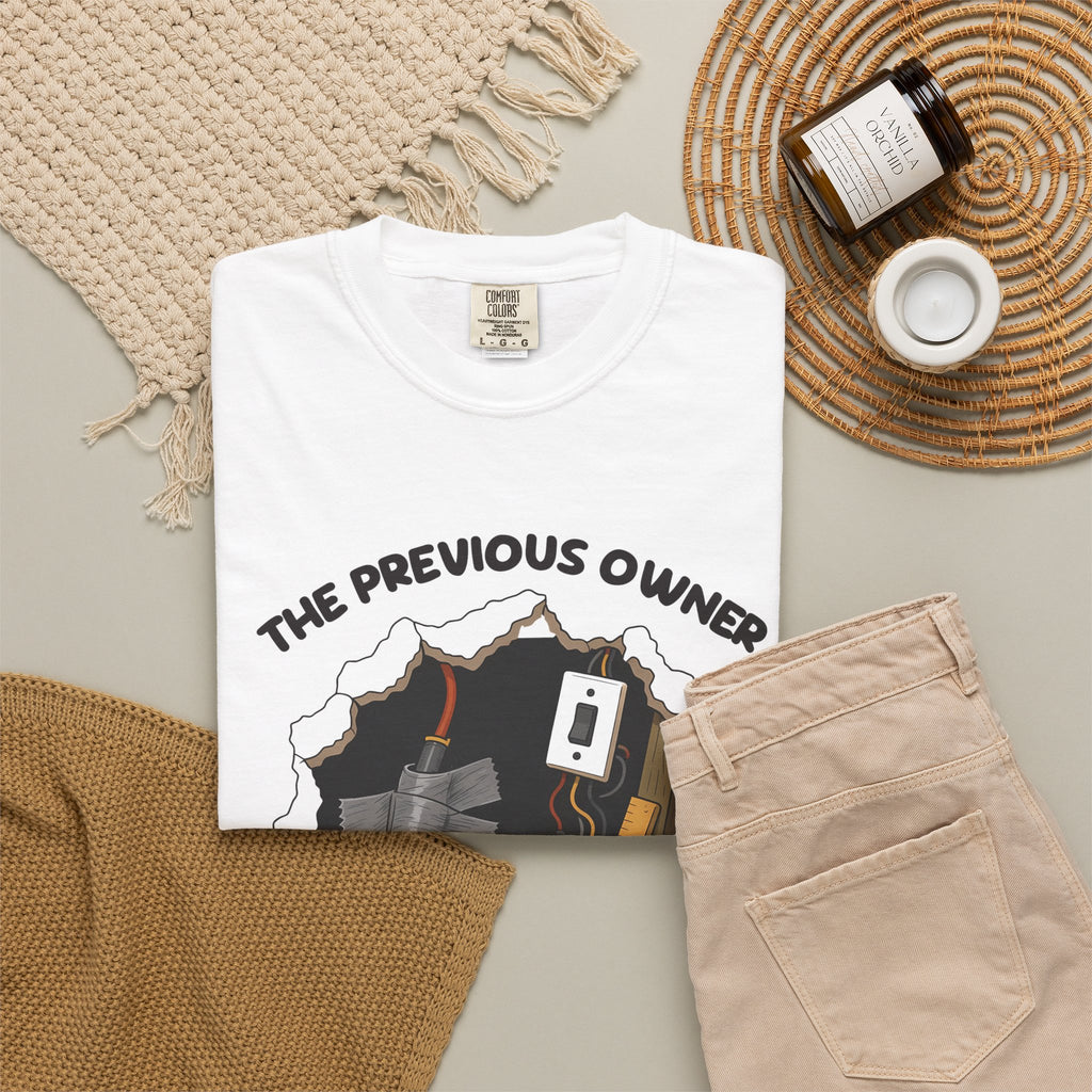 White The Previous Owner Did It Himself tee by Mildly Unavailable laid flat with folded pants and home decor