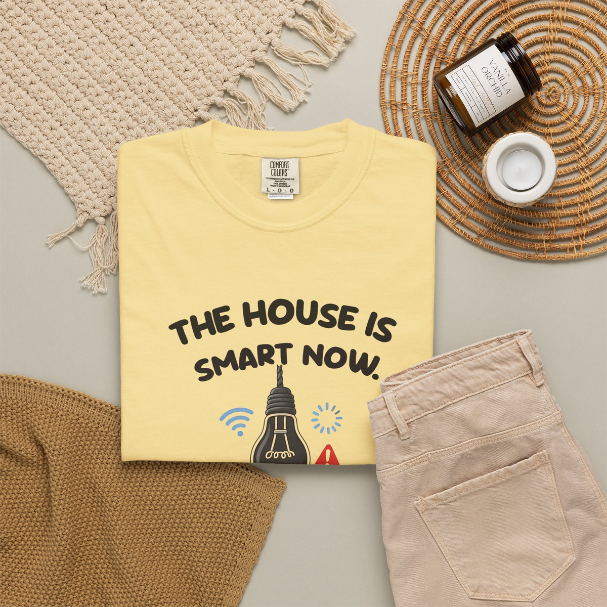 Butter The House Is Smart Now tee by Mildly Unavailable laid flat with folded pants and home decor