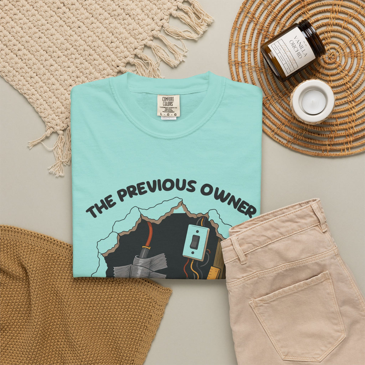 Chalky Mint The Previous Owner Did It Himself tee by Mildly Unavailable laid flat with folded pants and home decor