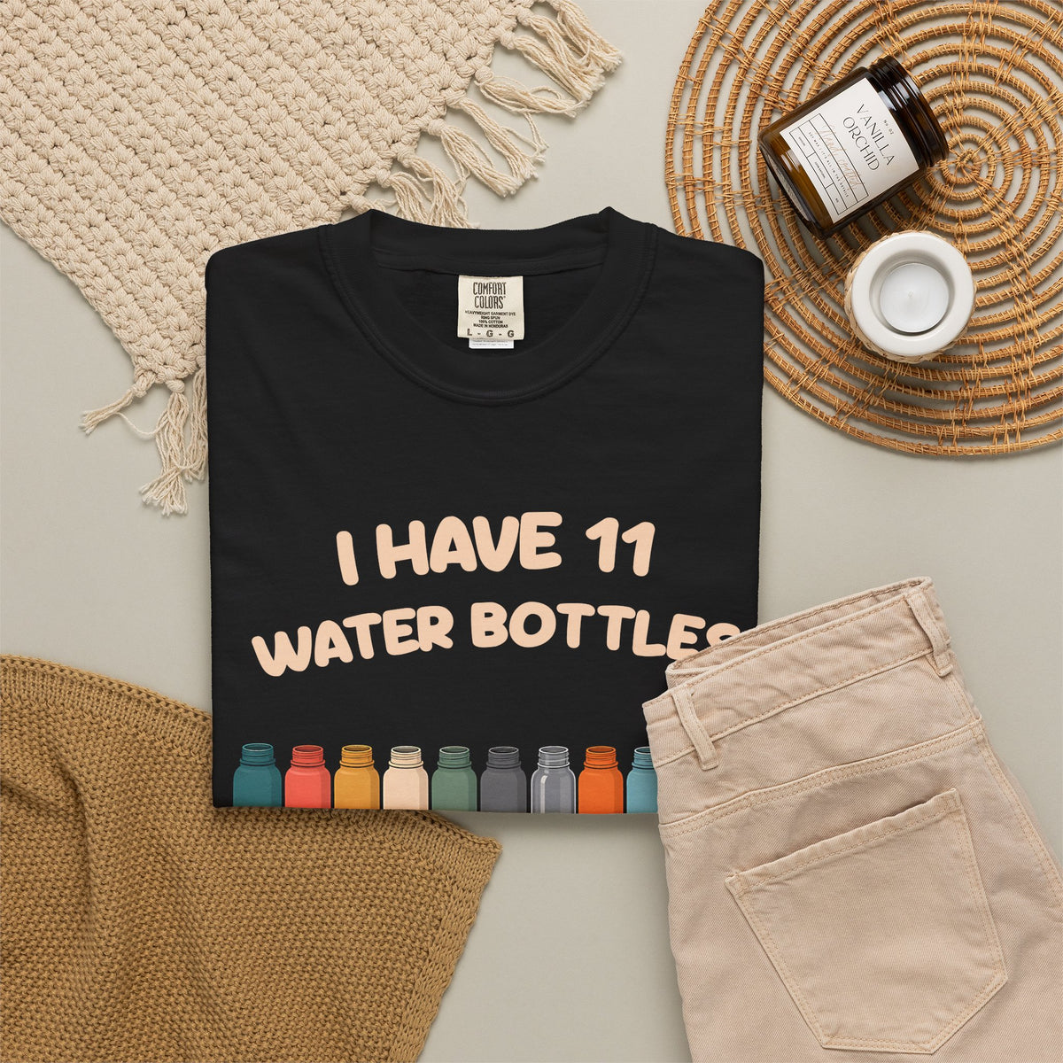 Black 11 Water Bottles, No Lids tee by Mildly Unavailable laid flat with folded pants and home decor
