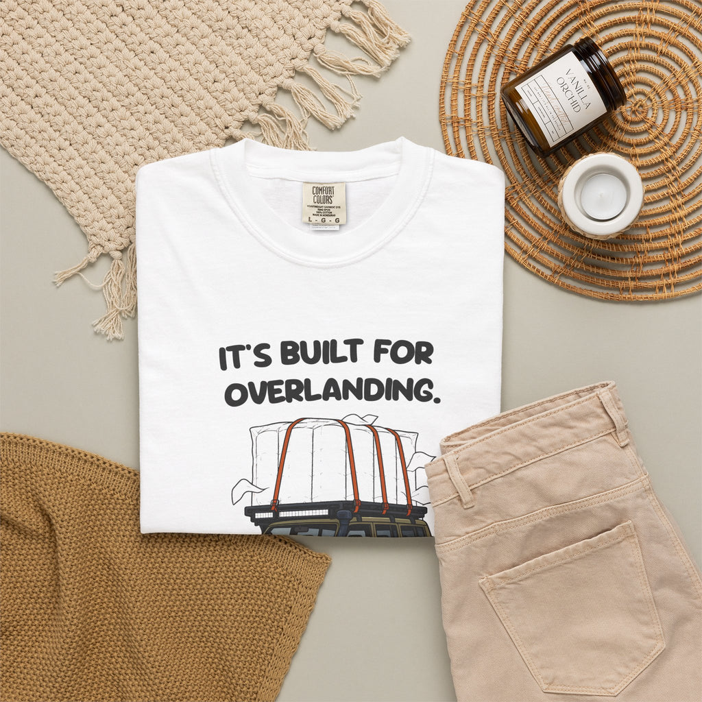 White Built for Overlanding tee by Mildly Unavailable laid flat with folded pants and home decor