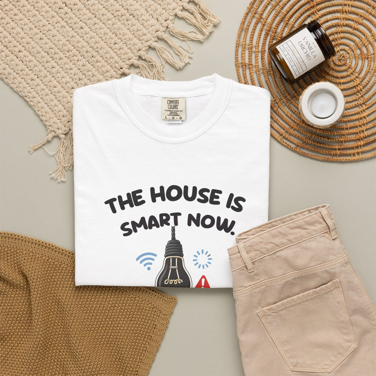 White The House Is Smart Now tee by Mildly Unavailable laid flat with folded pants and home decor