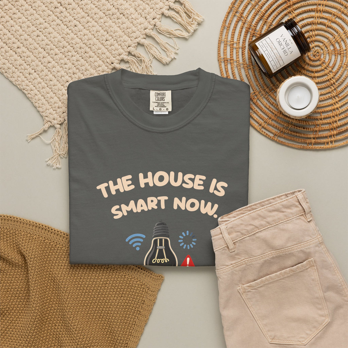 Pepper The House Is Smart Now tee by Mildly Unavailable laid flat with folded pants and home decor