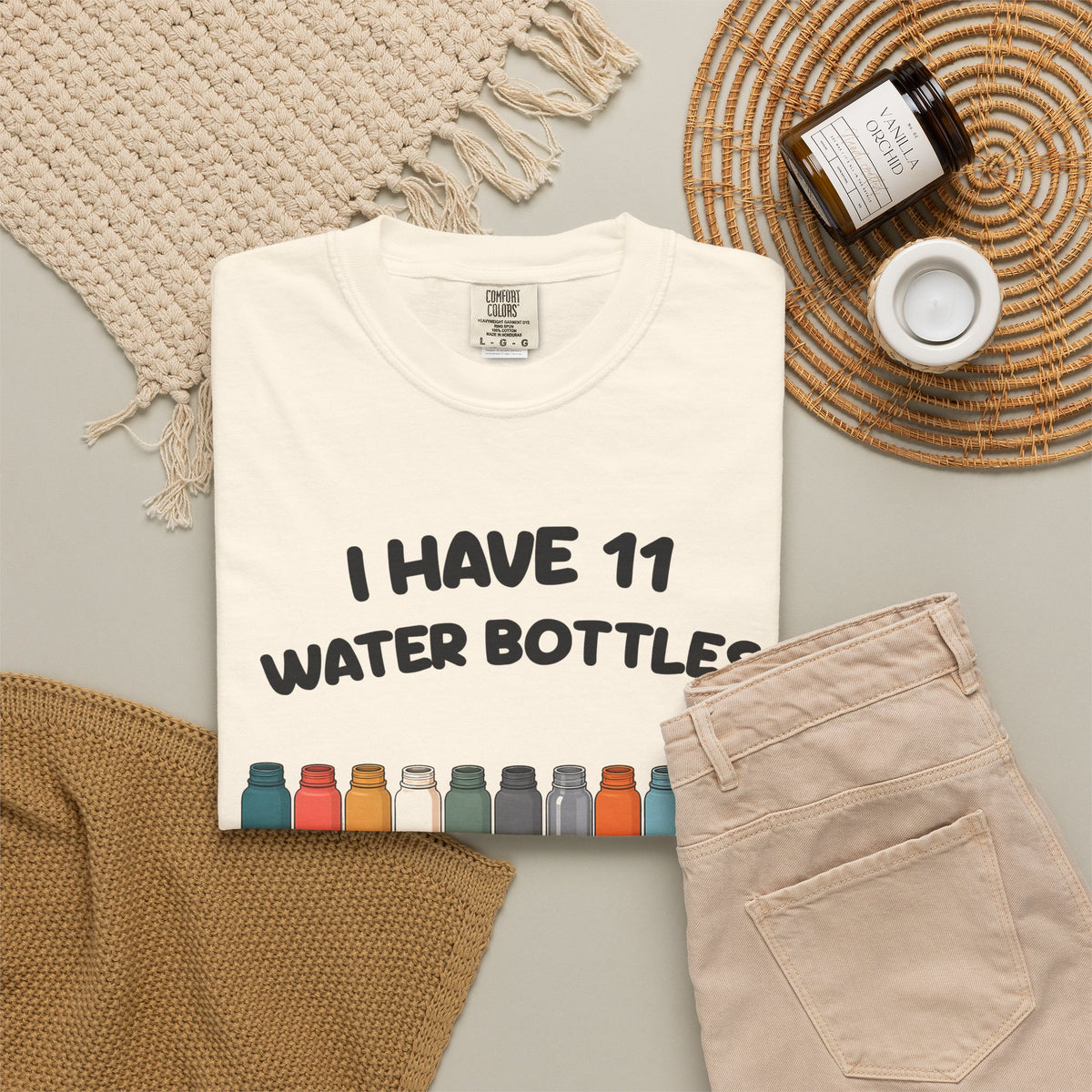 Ivory 11 Water Bottles, No Lids tee by Mildly Unavailable laid flat with folded pants and home decor