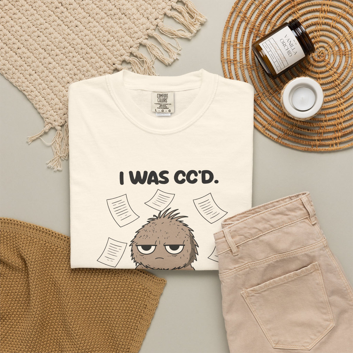 Ivory I Was CC'd Murray tee by Mildly Unavailable laid flat with folded pants and home decor