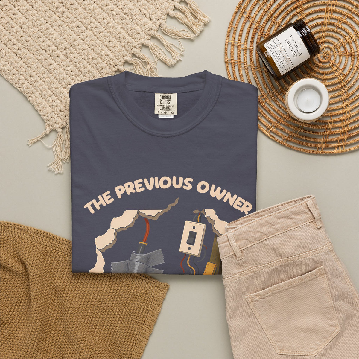 Navy The Previous Owner Did It Himself tee by Mildly Unavailable laid flat with folded pants and home decor