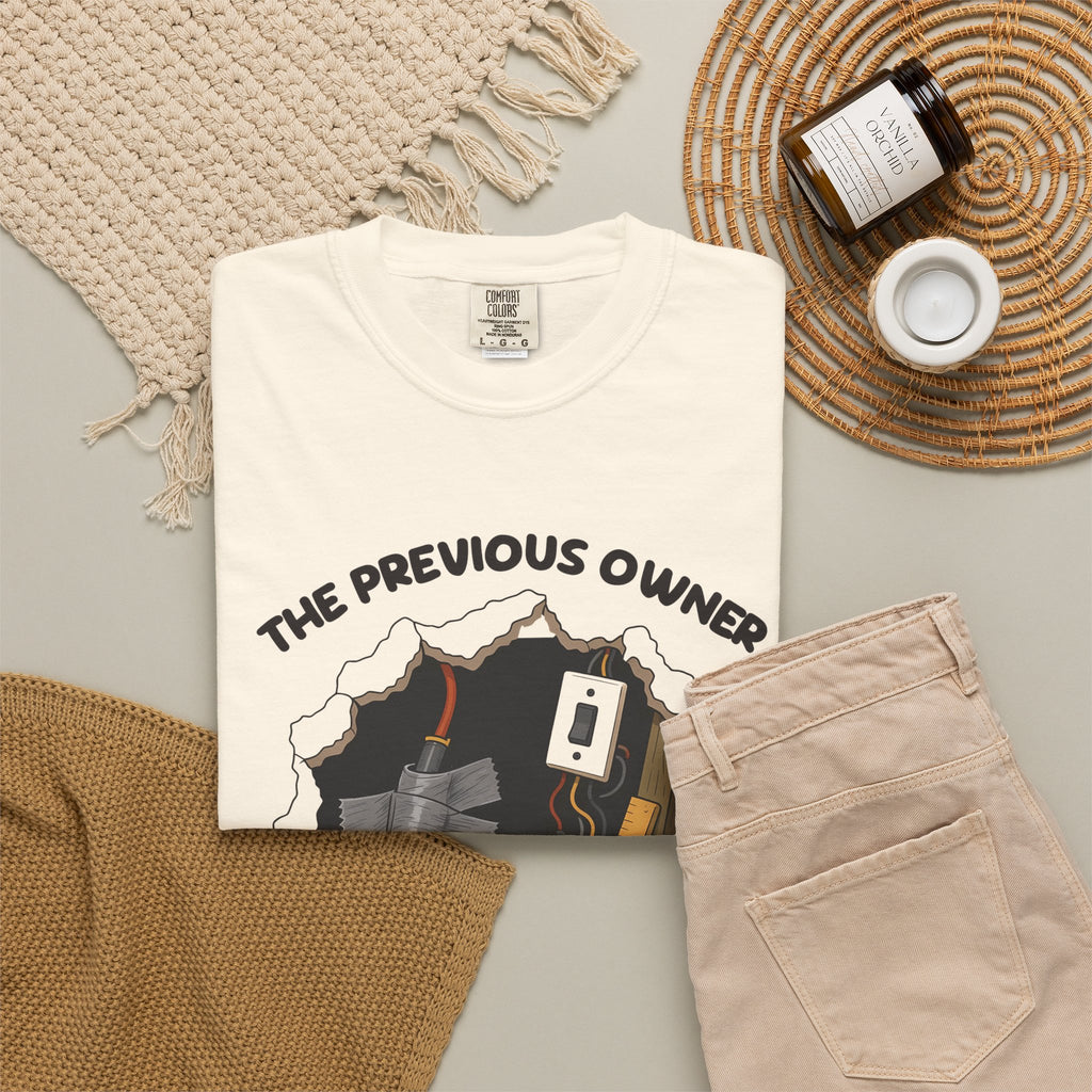 Ivory The Previous Owner Did It Himself tee by Mildly Unavailable laid flat with folded pants and home decor