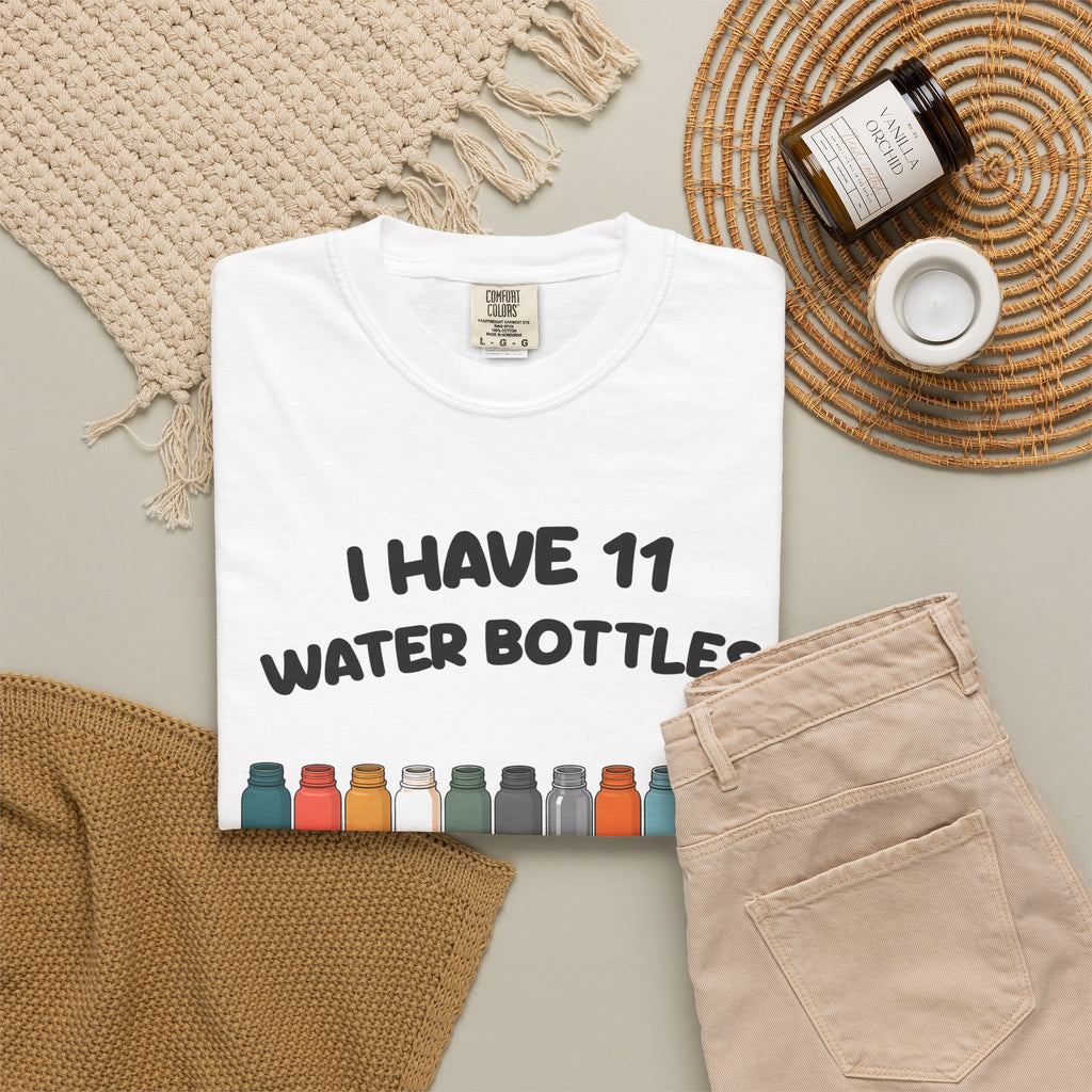 White 11 Water Bottles, No Lids tee by Mildly Unavailable laid flat with folded pants and home decor
