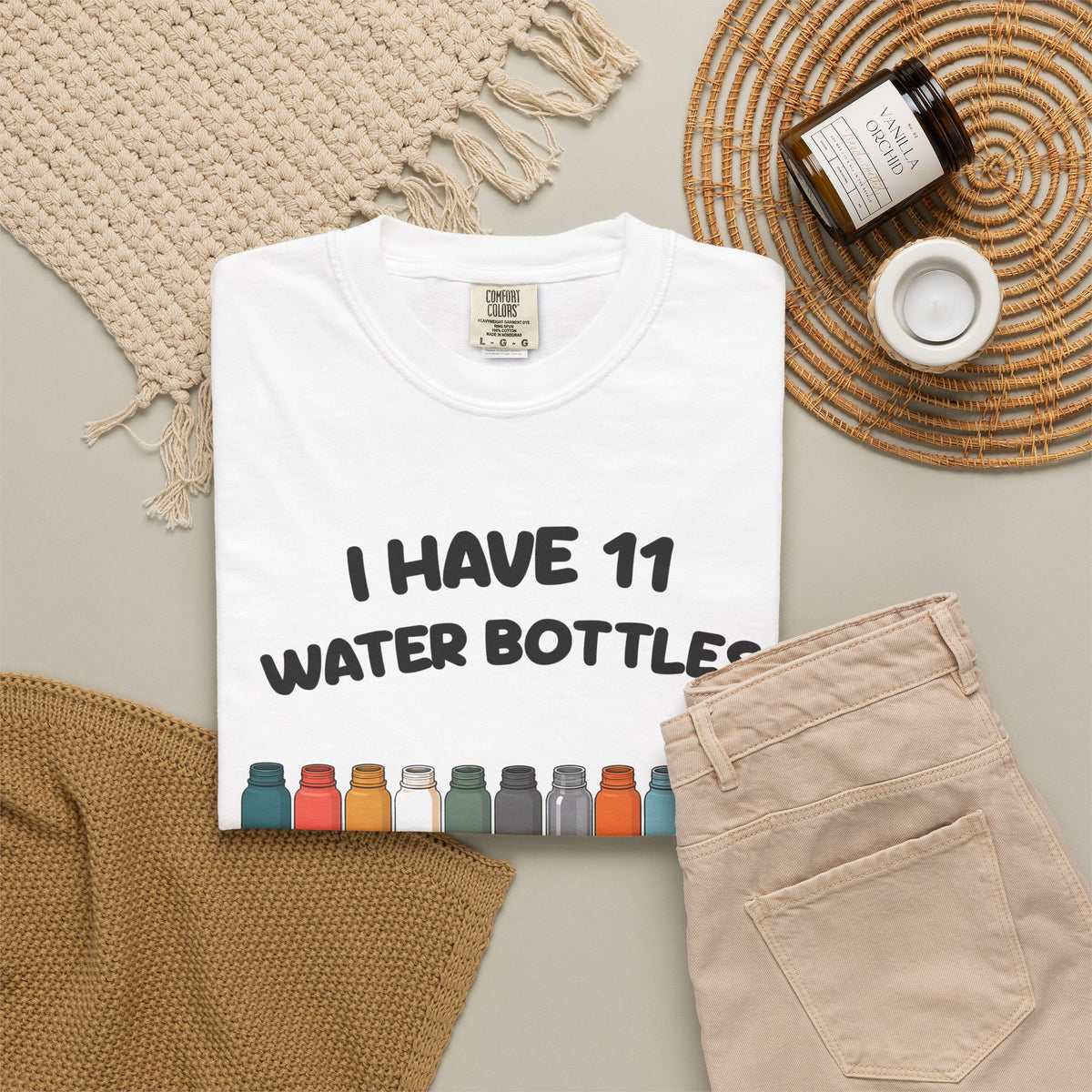 White 11 Water Bottles, No Lids tee by Mildly Unavailable laid flat with folded pants and home decor