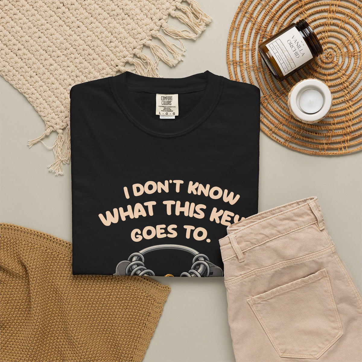 Black I Don't Know What This Key Goes To tee by Mildly Unavailable laid flat with folded pants and home decor
