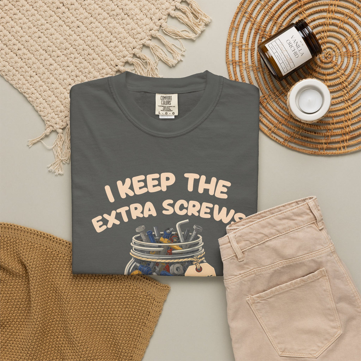 Pepper I Keep the Extra Screws tee by Mildly Unavailable laid flat with folded pants and home decor