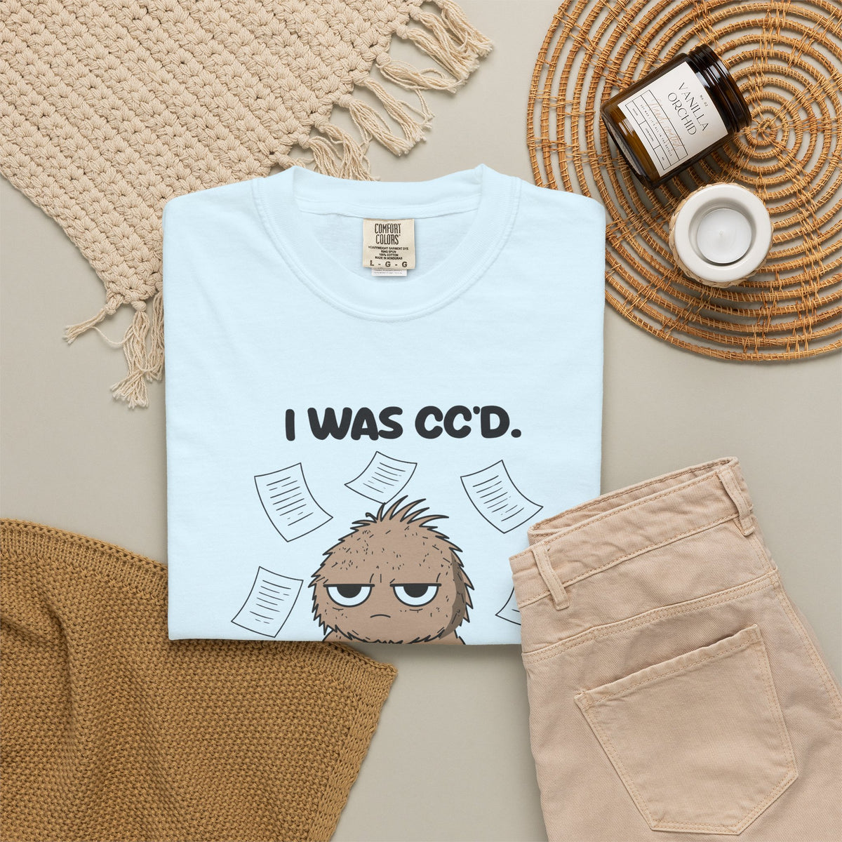 Chambray I Was CC'd Murray tee by Mildly Unavailable laid flat with folded pants and home decor