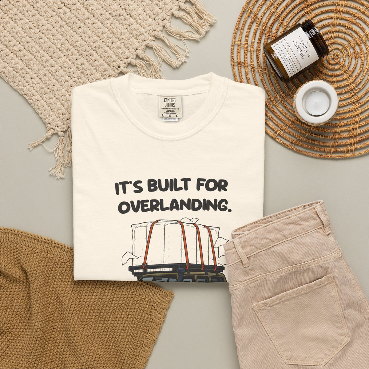 Ivory Built for Overlanding tee by Mildly Unavailable laid flat with folded pants and home decor
