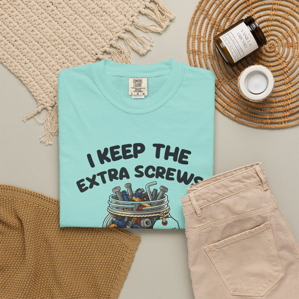 Chalky Mint I Keep the Extra Screws tee by Mildly Unavailable laid flat with folded pants and home decor